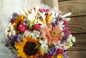 Giant sunflowers tango with tangerine zinnias on the gate of a tiny stone chapel in Baldwin, Kansas, welcoming guests to the wedding of Darci Mathison and Patrick Wedel.
